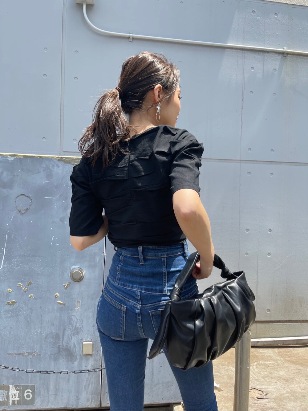 ブラック系のサンダル、ブラック系のハンドバッグ、ブラック系のTシャツ/カットソーを着用したレディースの夏コーディネートの3枚目の写真