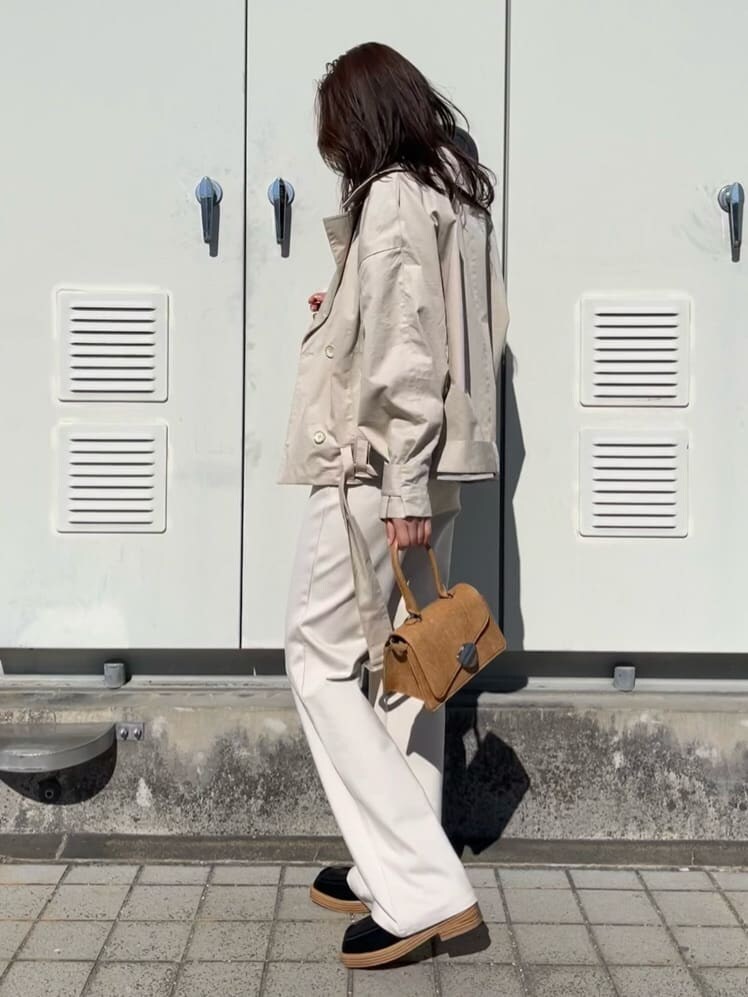 ベージュ系のトレンチコート、ホワイト系のその他パンツ、ブラウン系のハンドバッグを着用したレディースの冬コーディネートの2枚目の写真