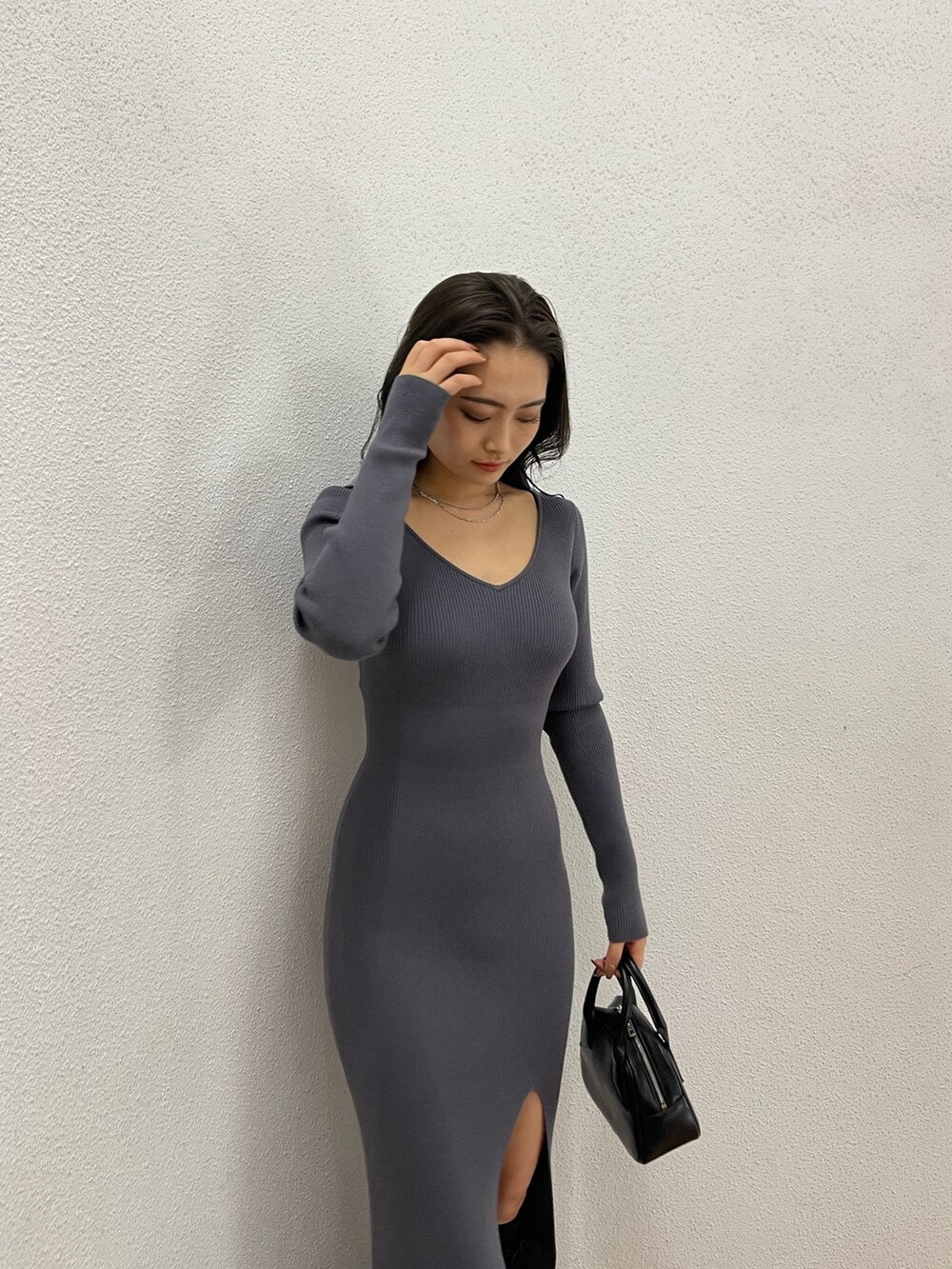 グレー系のワンピース、ブラック系のハンドバッグ、ブラック系のブーツを着用したレディースの冬コーディネートの2枚目の写真