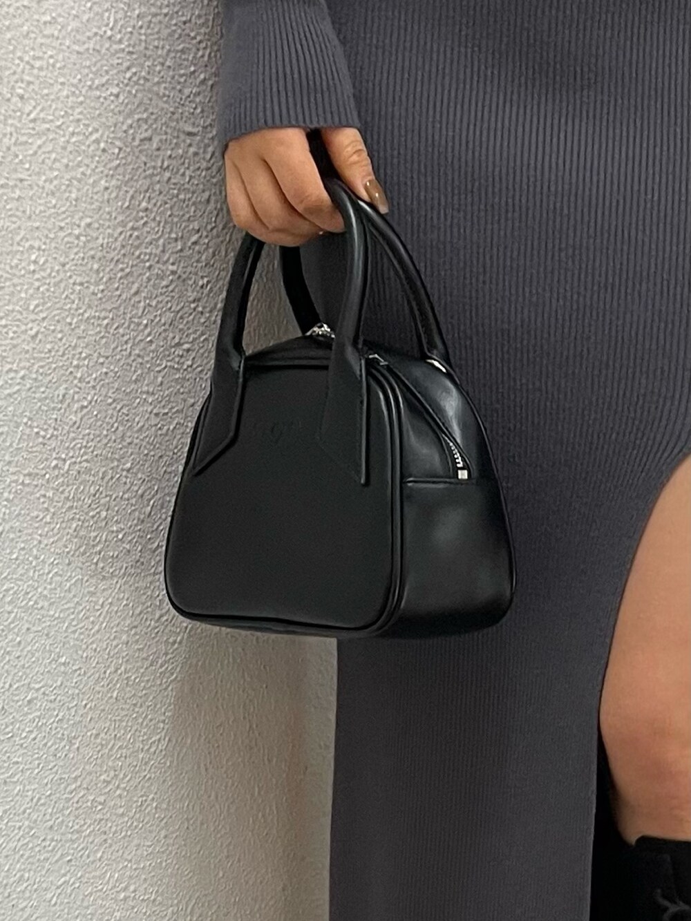 グレー系のワンピース、ブラック系のハンドバッグ、ブラック系のブーツを着用したレディースの冬コーディネートの6枚目の写真