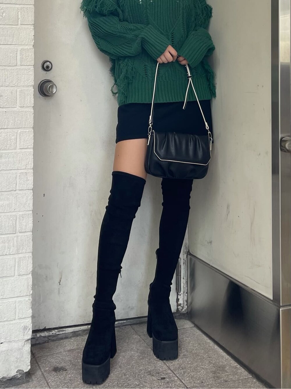 グリーン系のニット/セーター、ブラック系のブーツ、ブラック系のショルダーバッグを着用したレディースの秋コーディネートの5枚目の写真