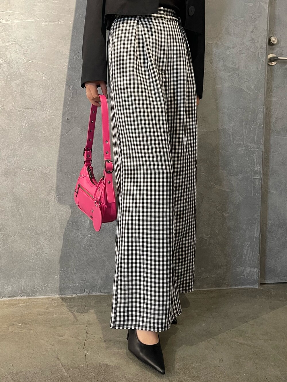 ピンク系のハンドバッグ、ブラック系のパンプス、ブラック系のテーラードジャケットを着用したレディースの冬コーディネートの6枚目の写真