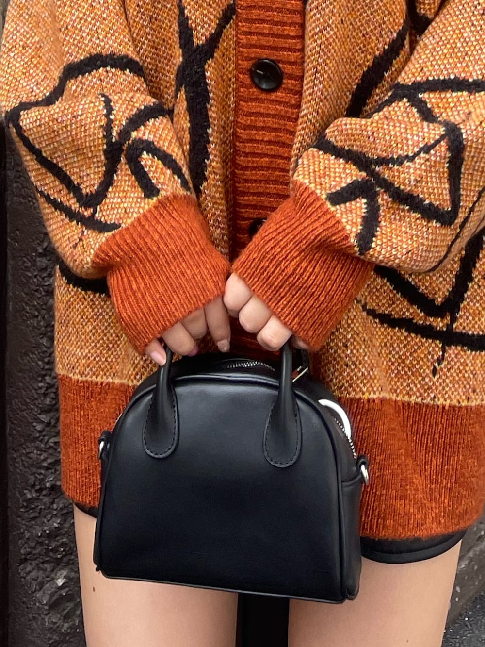 オレンジ系のニット/セーター、ブラック系のハンドバッグ、ブラック系のブーツを着用したレディースの秋コーディネートの8枚目の写真