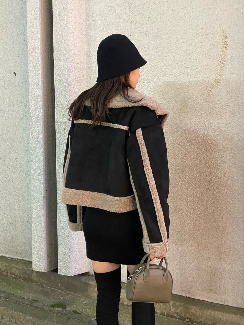 ブラック系のムートンコート、ブラウン系のハンドバッグ、ブラック系のブーツを着用したレディースの秋コーディネートの5枚目の写真