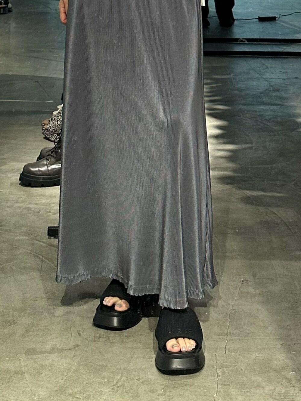 グレー系のスカート、ブラック系のサンダル、ホワイト系のTシャツ/カットソーを着用したレディースの夏コーディネートの7枚目の写真