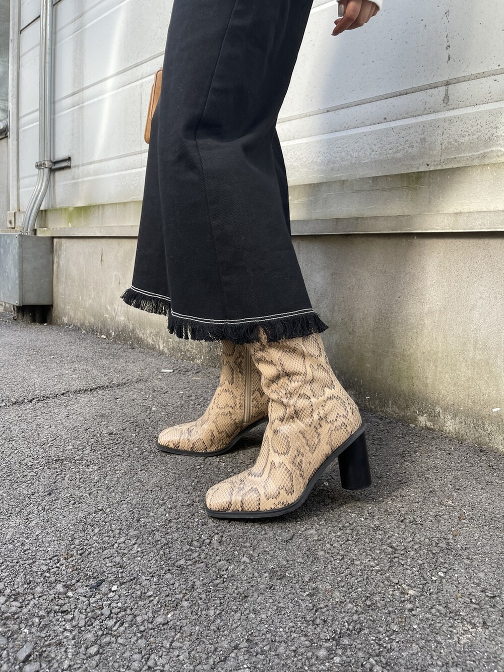 ブラック系のスカート、ホワイト系のTシャツ/カットソー、ブラウン系のハンドバッグを着用したレディースの冬コーディネートの9枚目の写真