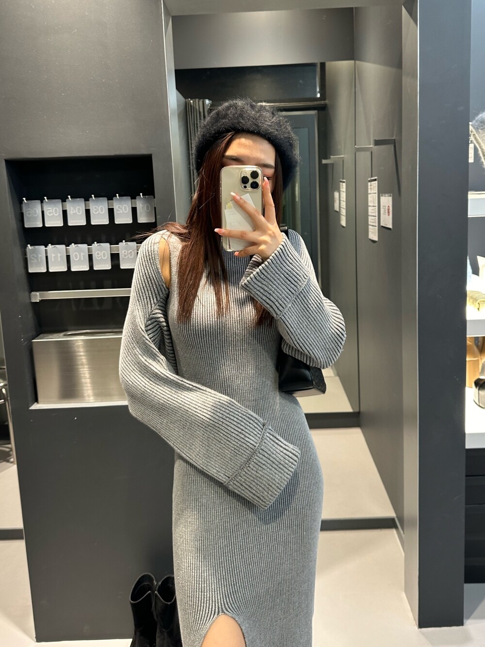 グレー系のワンピース、ブラック系のブーツ、ブラック系のハンドバッグを着用したレディースの冬コーディネートの2枚目の写真