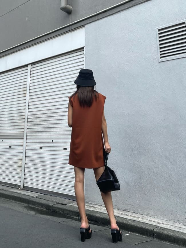 オレンジ系のワンピース、ブラック系のハンドバッグ、ブラック系のサンダルを着用したレディースの夏コーディネートの4枚目の写真