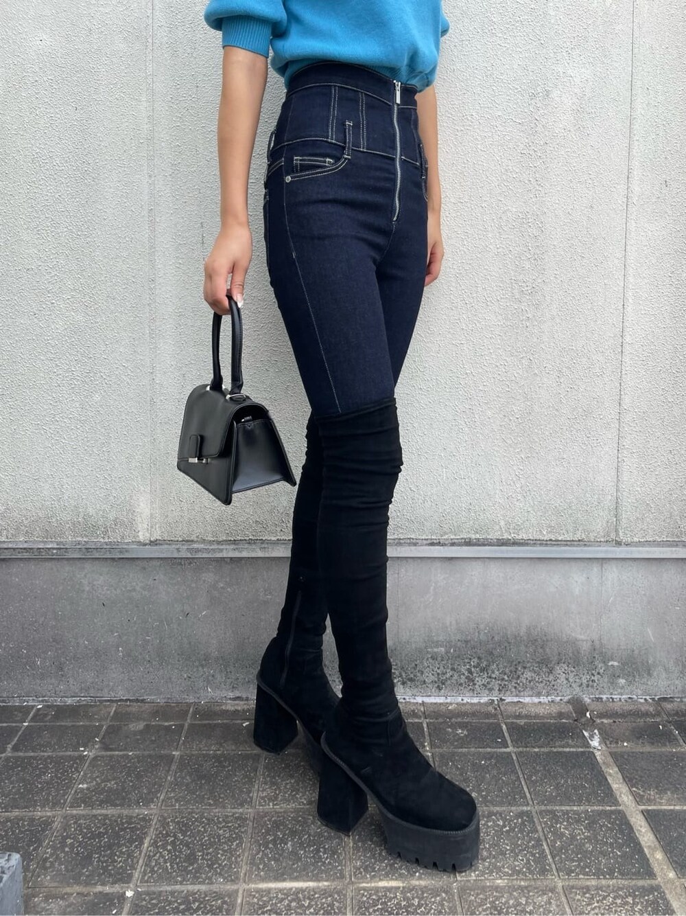 ブラック系のハンドバッグ、ブルー系のデニムパンツ、ブルー系のニット/セーターを着用したレディースの秋コーディネートの5枚目の写真