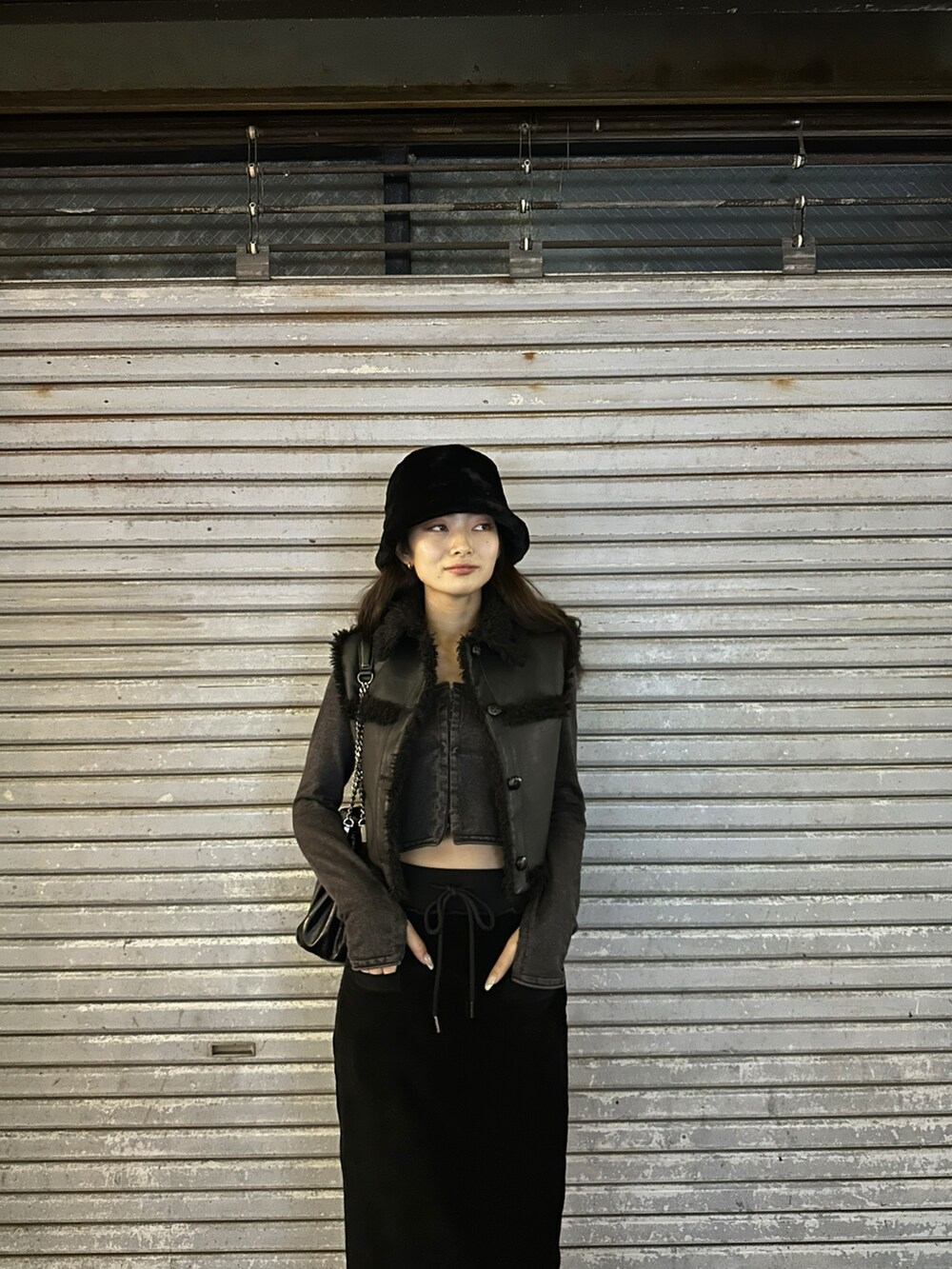 ブラック系のスカート、ブラック系のブーツ、ブラック系のハットを着用したレディースの冬コーディネートの6枚目の写真