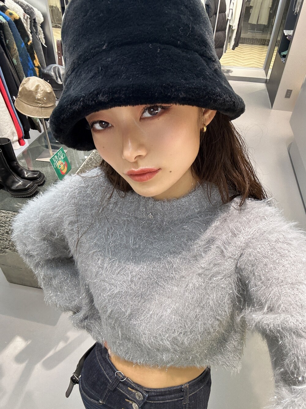 グレー系のニット/セーター、ブルー系のデニムパンツ、ブラック系のハンドバッグを着用したレディースの秋コーディネートの7枚目の写真