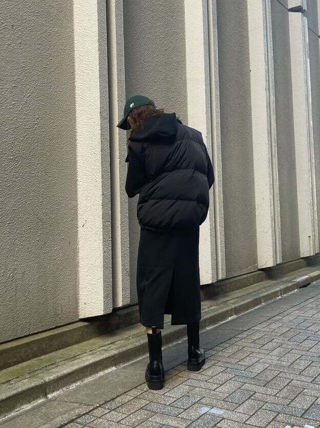 ブラック系のダウンベスト、ブラック系のワンピース、ブラック系のブーツを着用したレディースの秋コーディネートの5枚目の写真