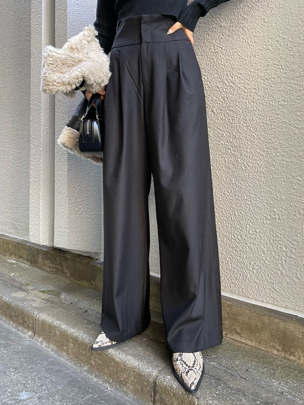 ブラック系のニット/セーター、ブラック系のその他パンツ、ブラック系のハンドバッグを着用したレディースの冬コーディネートの8枚目の写真