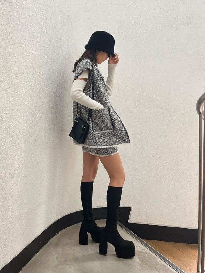 ホワイト系のニット/セーター、ブラック系のブーツ、グレー系のベストを着用したレディースの秋コーディネートの3枚目の写真