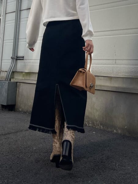 ブラック系のスカート、ホワイト系のTシャツ/カットソー、ブラウン系のハンドバッグを着用したレディースの冬コーディネートの7枚目の写真