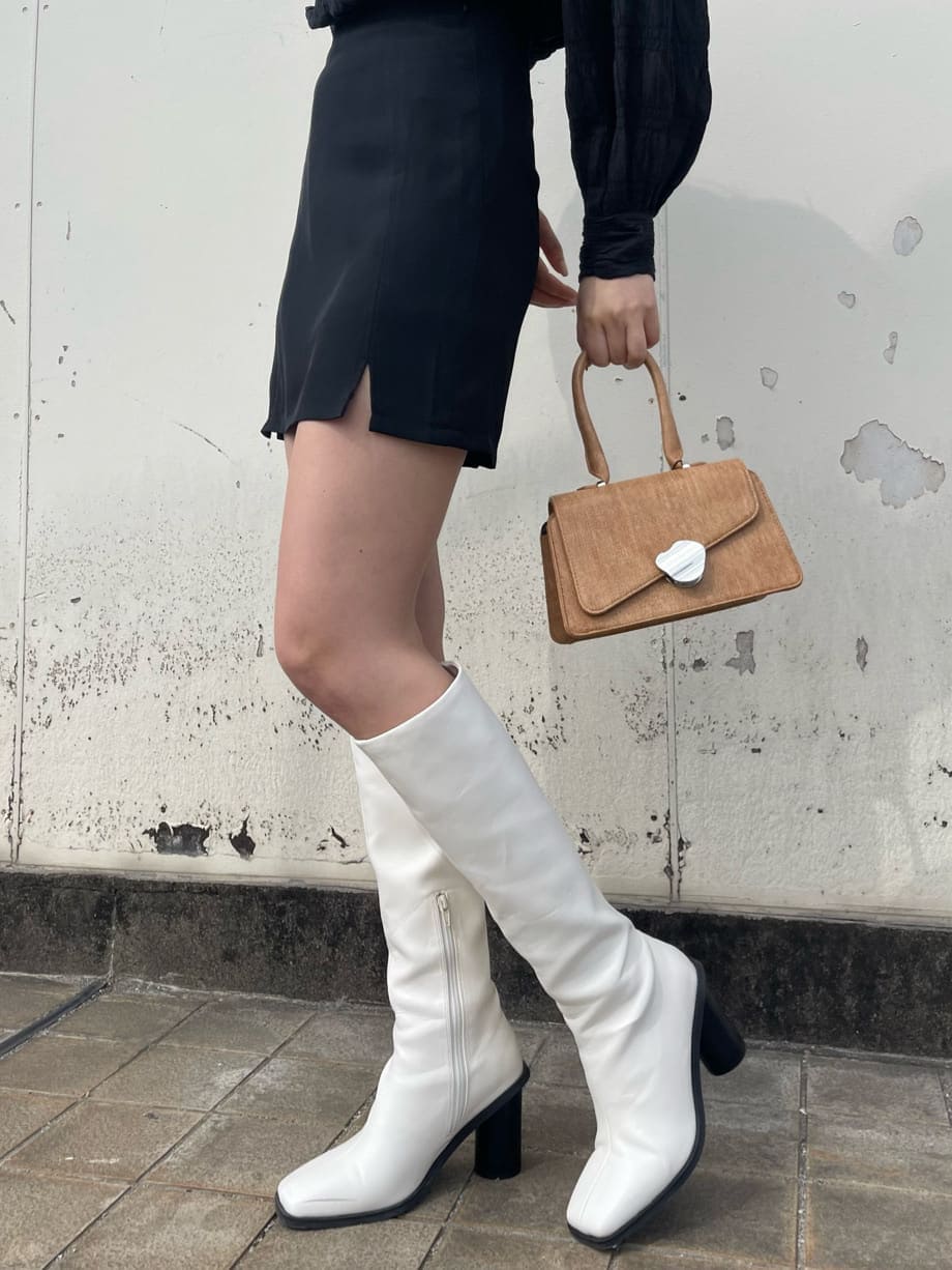 ホワイト系のブーツ、ブラウン系のハンドバッグ、ブラック系のシャツ/ブラウスを着用したレディースの春コーディネートの7枚目の写真