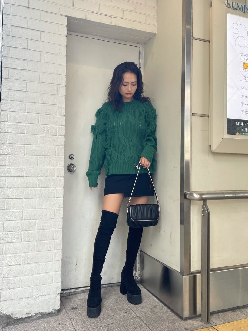 グリーン系のニット/セーター、ブラック系のブーツ、ブラック系のショルダーバッグを着用したレディースの秋コーディネートの2枚目の写真