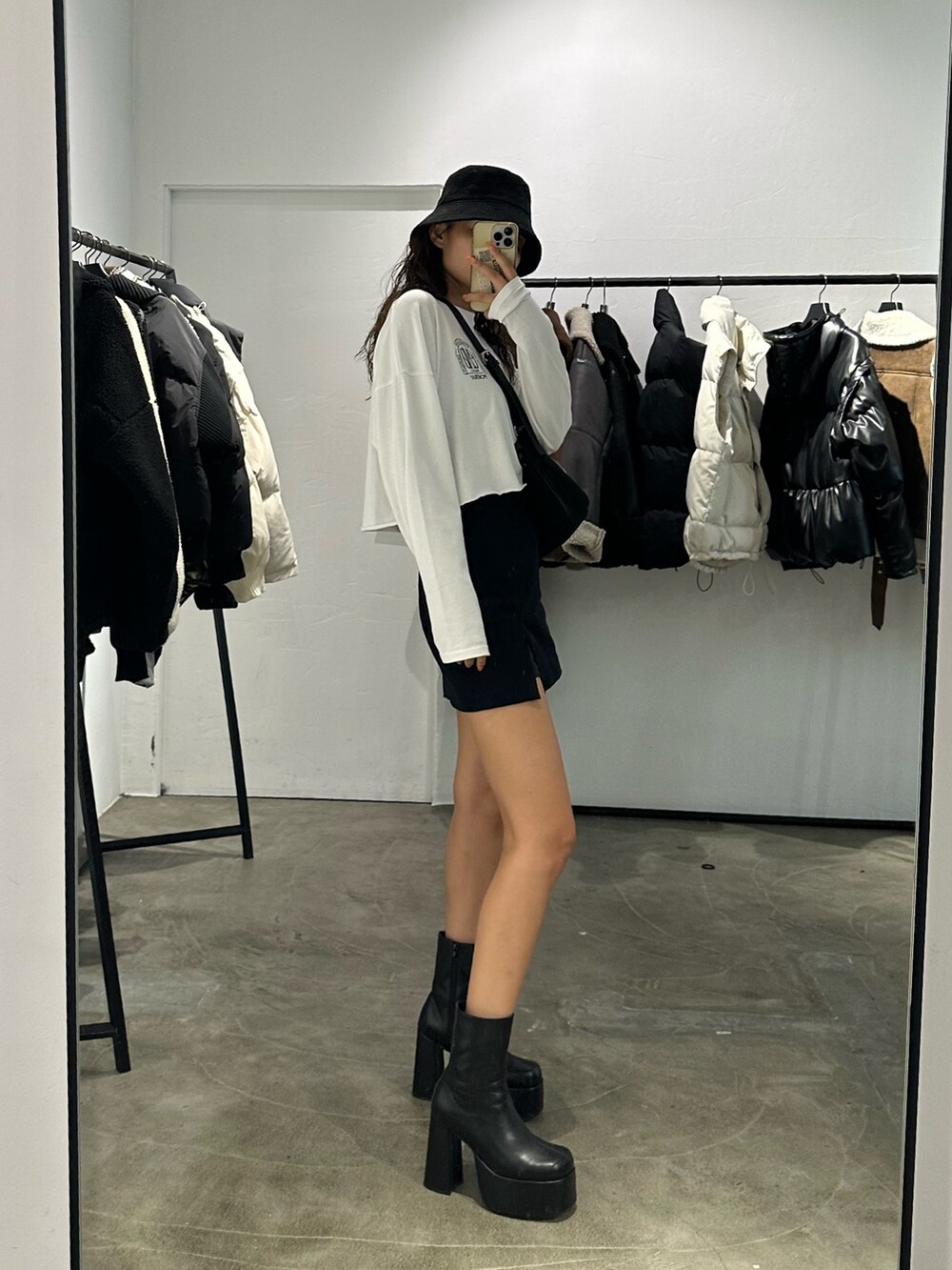 ブラック系のブーツ、ブラック系のスカート、ホワイト系のTシャツ/カットソーを着用したレディースの秋コーディネートの3枚目の写真