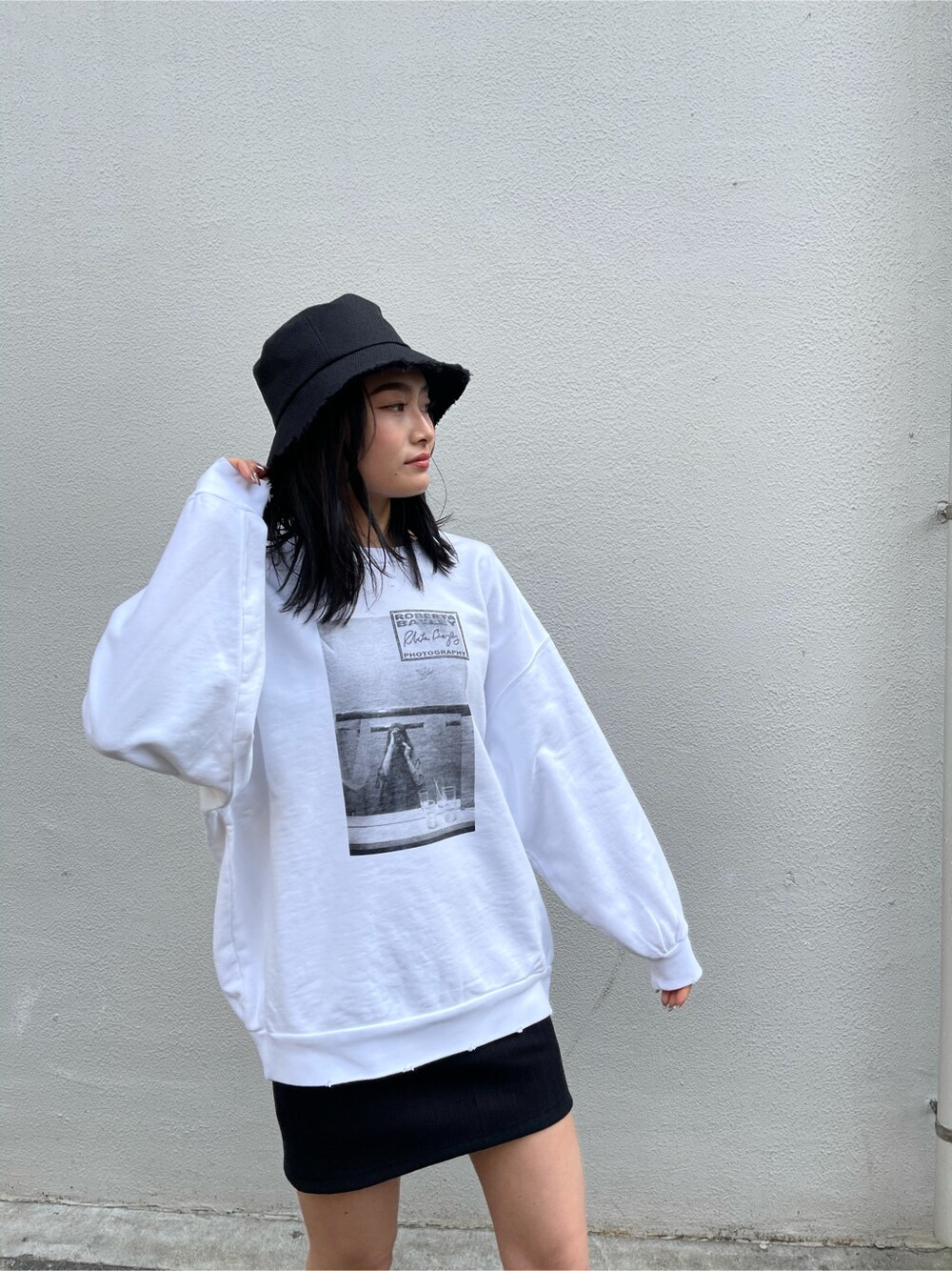 ブラック系のサンダル、ブラック系のスカート、ホワイト系のスウェットを着用したレディースの春コーディネートの2枚目の写真