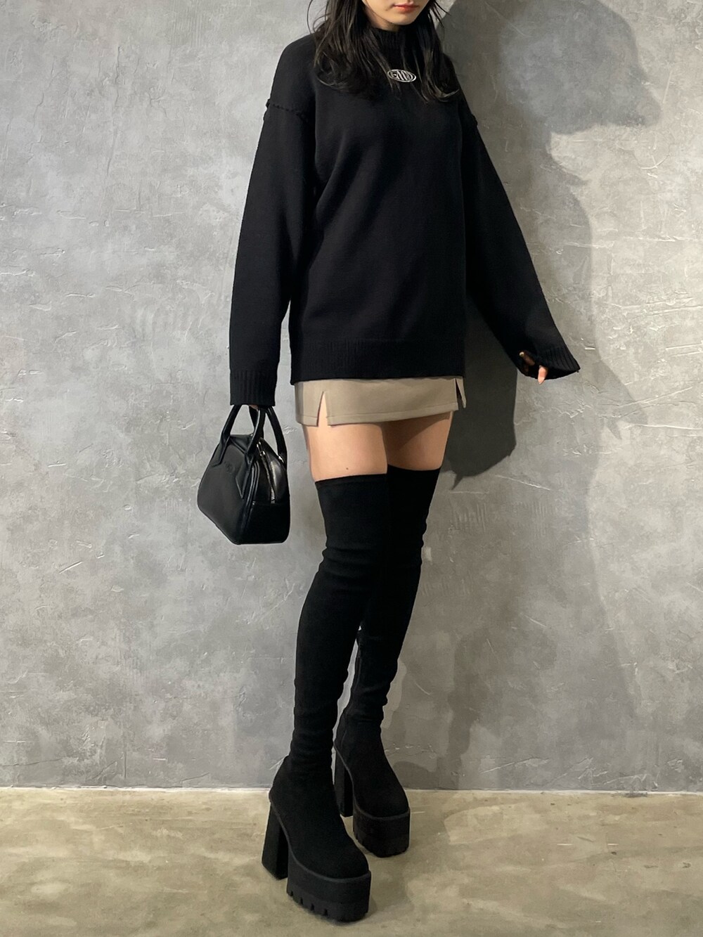 ブラック系のニット/セーター、ベージュ系のスカート、ブラック系のブーツを着用したレディースの冬コーディネートの3枚目の写真