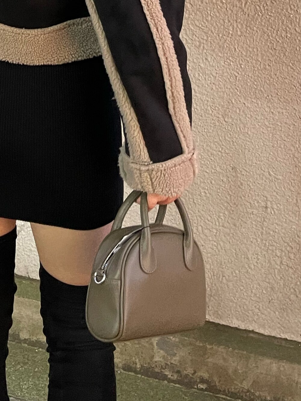 ブラック系のムートンコート、ブラウン系のハンドバッグ、ブラック系のブーツを着用したレディースの秋コーディネートの9枚目の写真