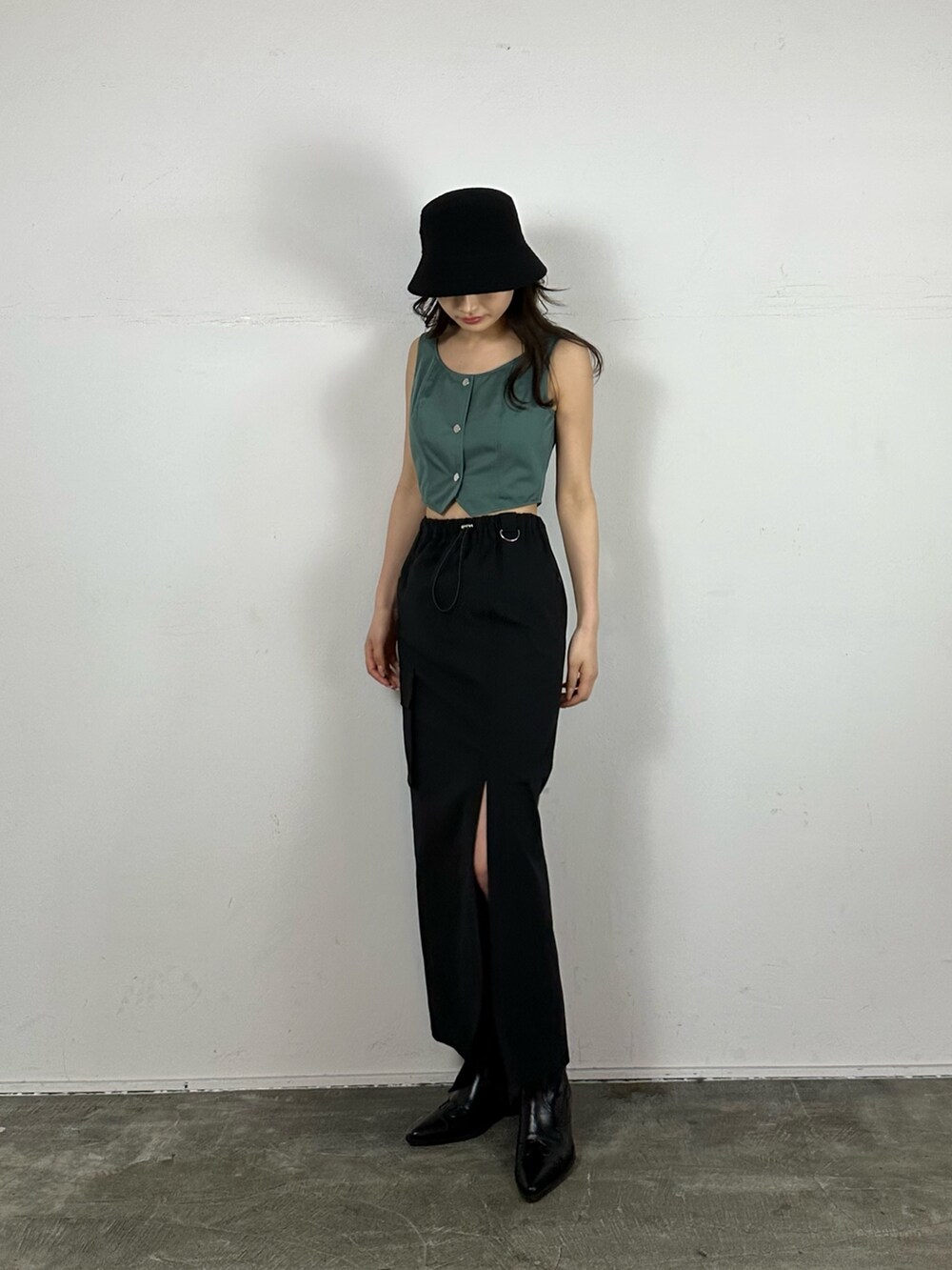 ブラック系のスカート、グリーン系のキャミソール、ブラック系のブーツを着用したレディースの春コーディネートの2枚目の写真