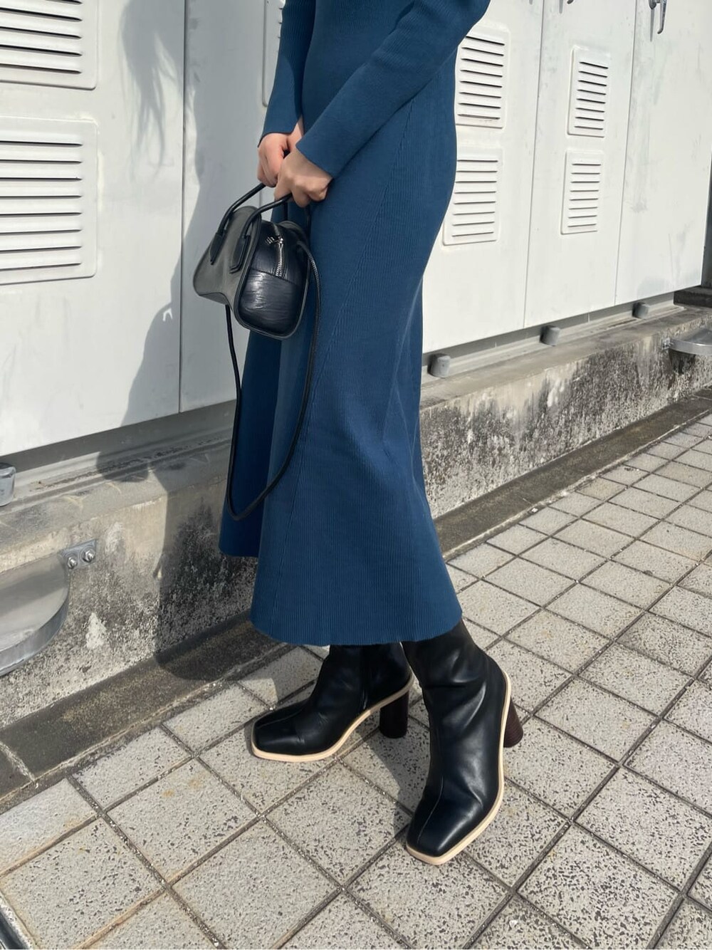ブラック系のブーツ、ブラック系のハンドバッグ、ブルー系のワンピースを着用したレディースの冬コーディネートの2枚目の写真