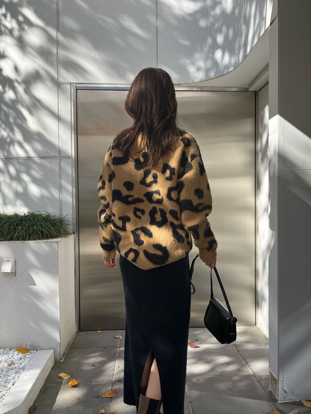 ベージュ系のニット/セーター、ブラウン系のブーツ、ブラック系のスカートを着用したレディースの秋コーディネートの6枚目の写真