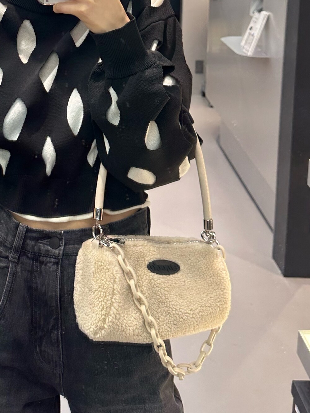 ブラック系のデニムパンツ、ホワイト系のハンドバッグ、ブラック系のローファーを着用したレディースの冬コーディネートの7枚目の写真