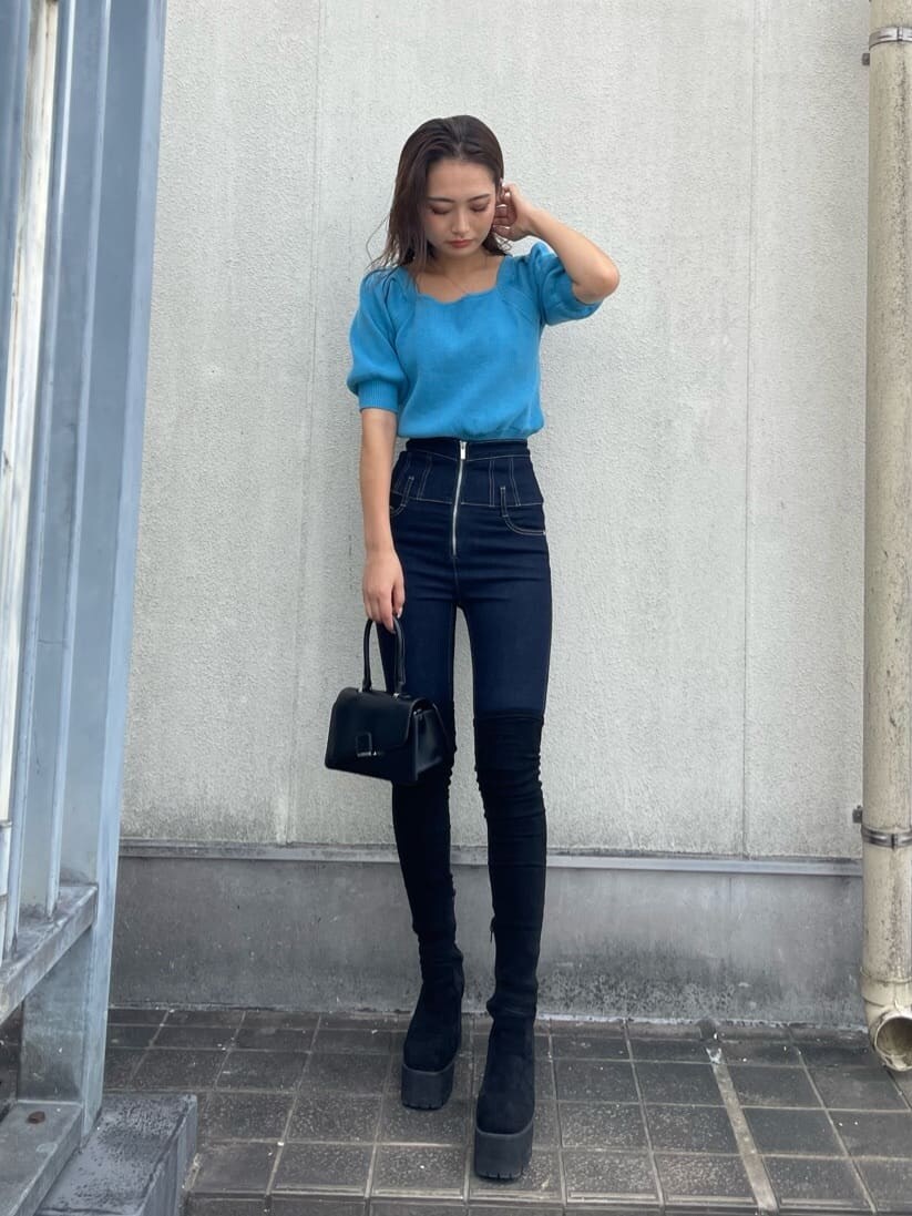 ブラック系のハンドバッグ、ブルー系のデニムパンツ、ブルー系のニット/セーターを着用したレディースの秋コーディネートの2枚目の写真