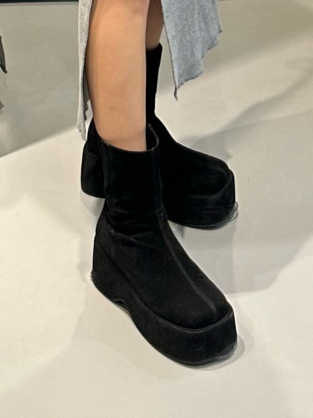 グレー系のワンピース、ブラック系のブーツ、ブラック系のハンドバッグを着用したレディースの冬コーディネートの7枚目の写真