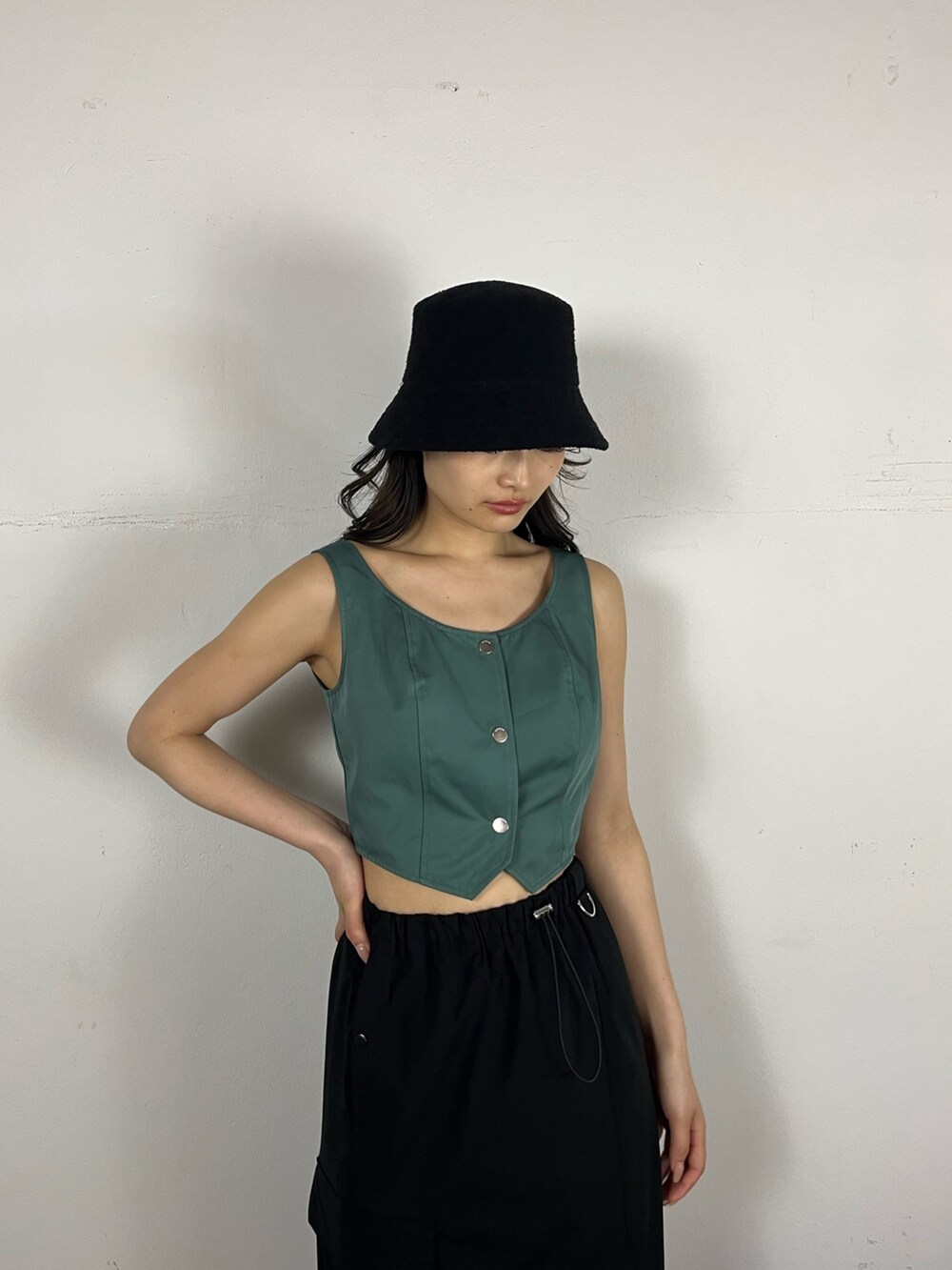 ブラック系のスカート、グリーン系のキャミソール、ブラック系のブーツを着用したレディースの春コーディネートの3枚目の写真