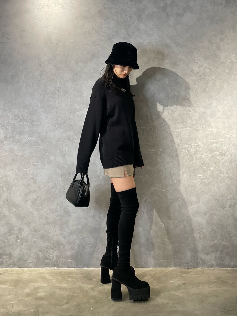 ブラック系のニット/セーター、ベージュ系のスカート、ブラック系のブーツを着用したレディースの冬コーディネートの2枚目の写真