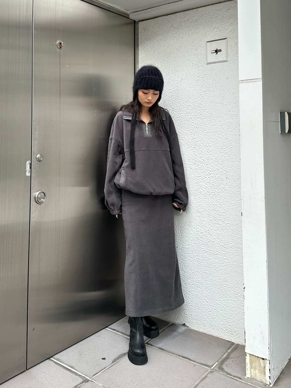 グレー系のTシャツ/カットソー、グレー系のスカート、ブラック系のブーツを着用したレディースの秋コーディネートの2枚目の写真