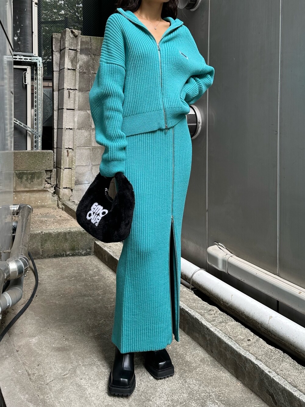 ブラック系のハンドバッグ、ブラック系のブーツ、ブルー系のスカートを着用したレディースの秋コーディネートの7枚目の写真