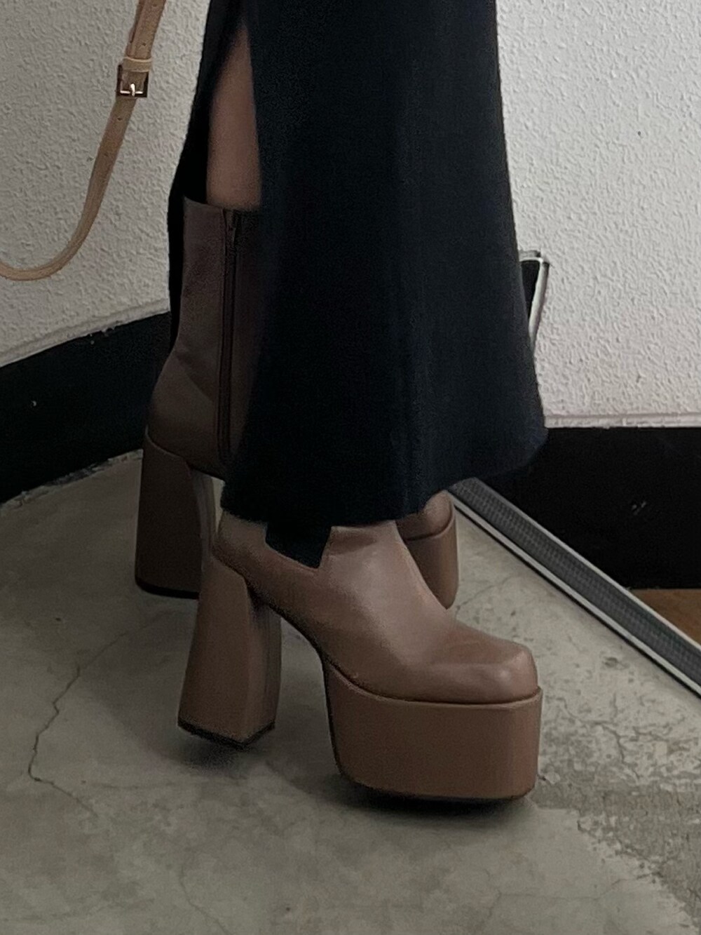 ベージュ系のニット/セーター、ブラウン系のブーツ、ブラック系のスカートを着用したレディースの秋コーディネートの8枚目の写真