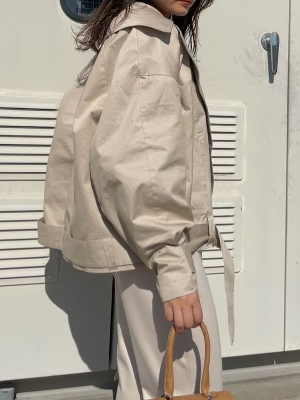 ベージュ系のトレンチコート、ホワイト系のその他パンツ、ブラウン系のハンドバッグを着用したレディースの冬コーディネートの4枚目の写真