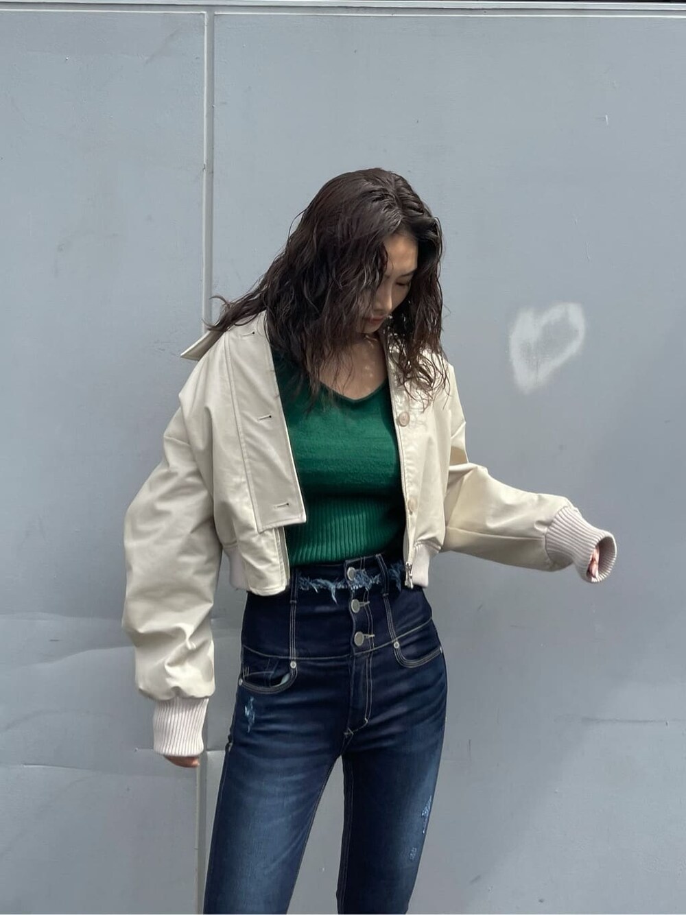 ホワイト系のブルゾン、ブラック系のブーツ、ブルー系のデニムパンツを着用したレディースの秋コーディネートの4枚目の写真