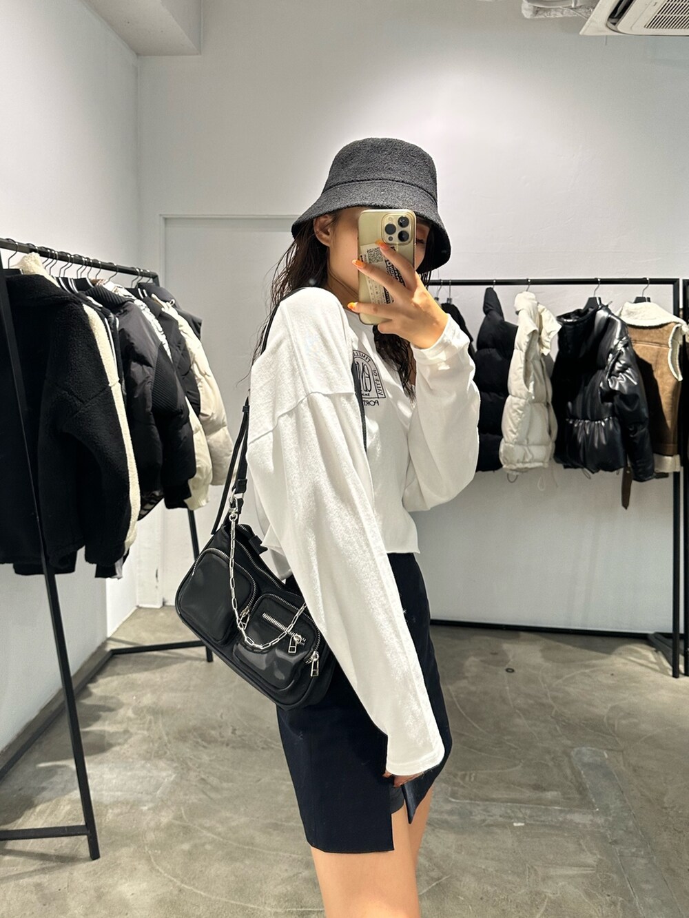 ブラック系のブーツ、ブラック系のスカート、ホワイト系のTシャツ/カットソーを着用したレディースの秋コーディネートの4枚目の写真