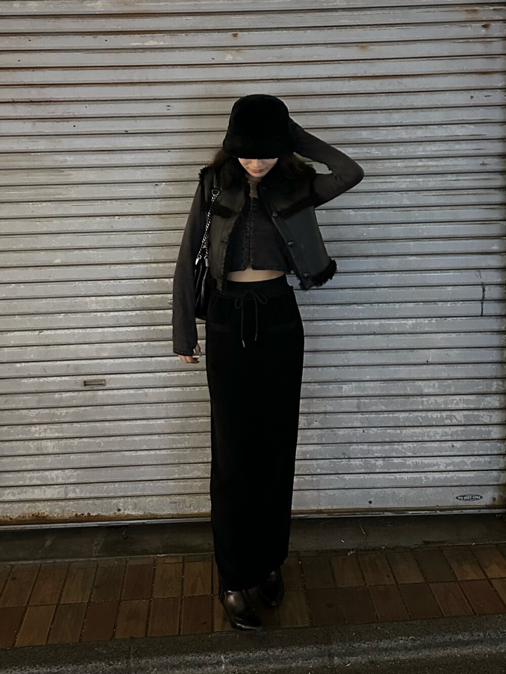 ブラック系のスカート、ブラック系のブーツ、ブラック系のハットを着用したレディースの冬コーディネートの2枚目の写真