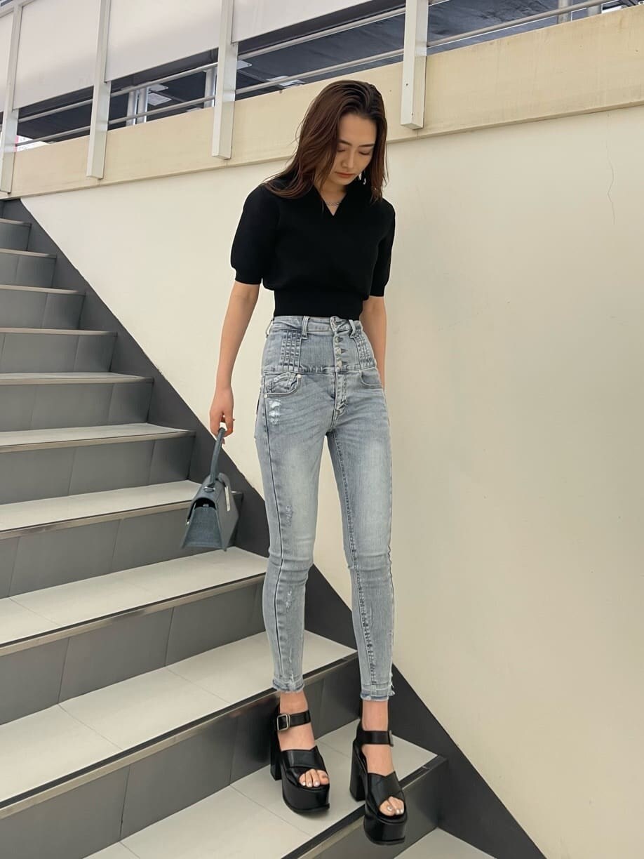 ブラック系のニット/セーター、ブルー系のハンドバッグ、ブラック系のサンダルを着用したレディースの春コーディネートの2枚目の写真