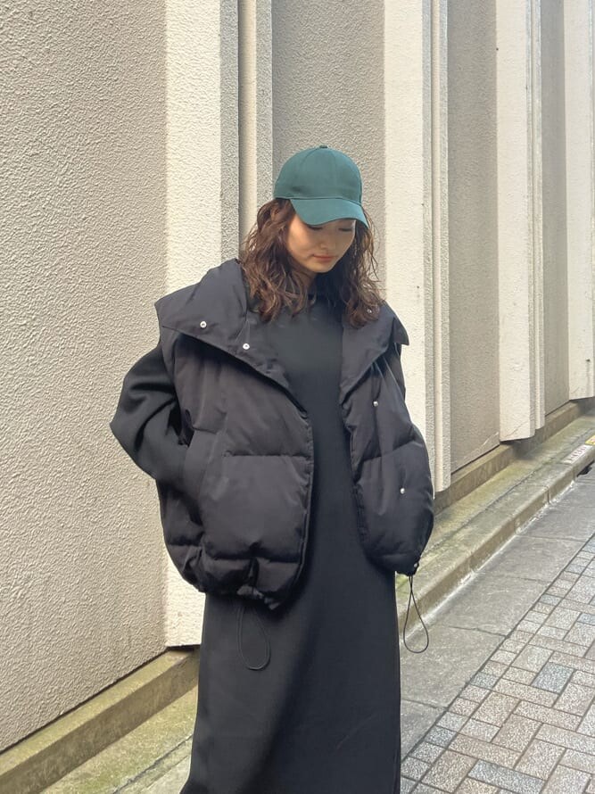 ブラック系のダウンベスト、ブラック系のワンピース、ブラック系のブーツを着用したレディースの秋コーディネートの3枚目の写真