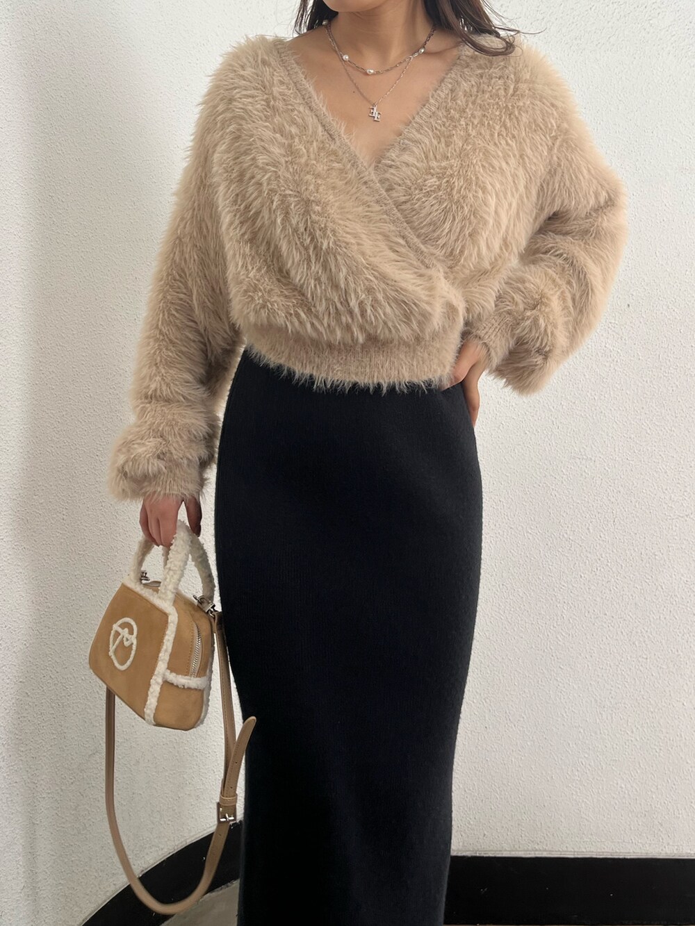 ホワイト系のニット/セーター、ベージュ系のハンドバッグ、ブラウン系のブーツを着用したレディースの秋コーディネートの4枚目の写真