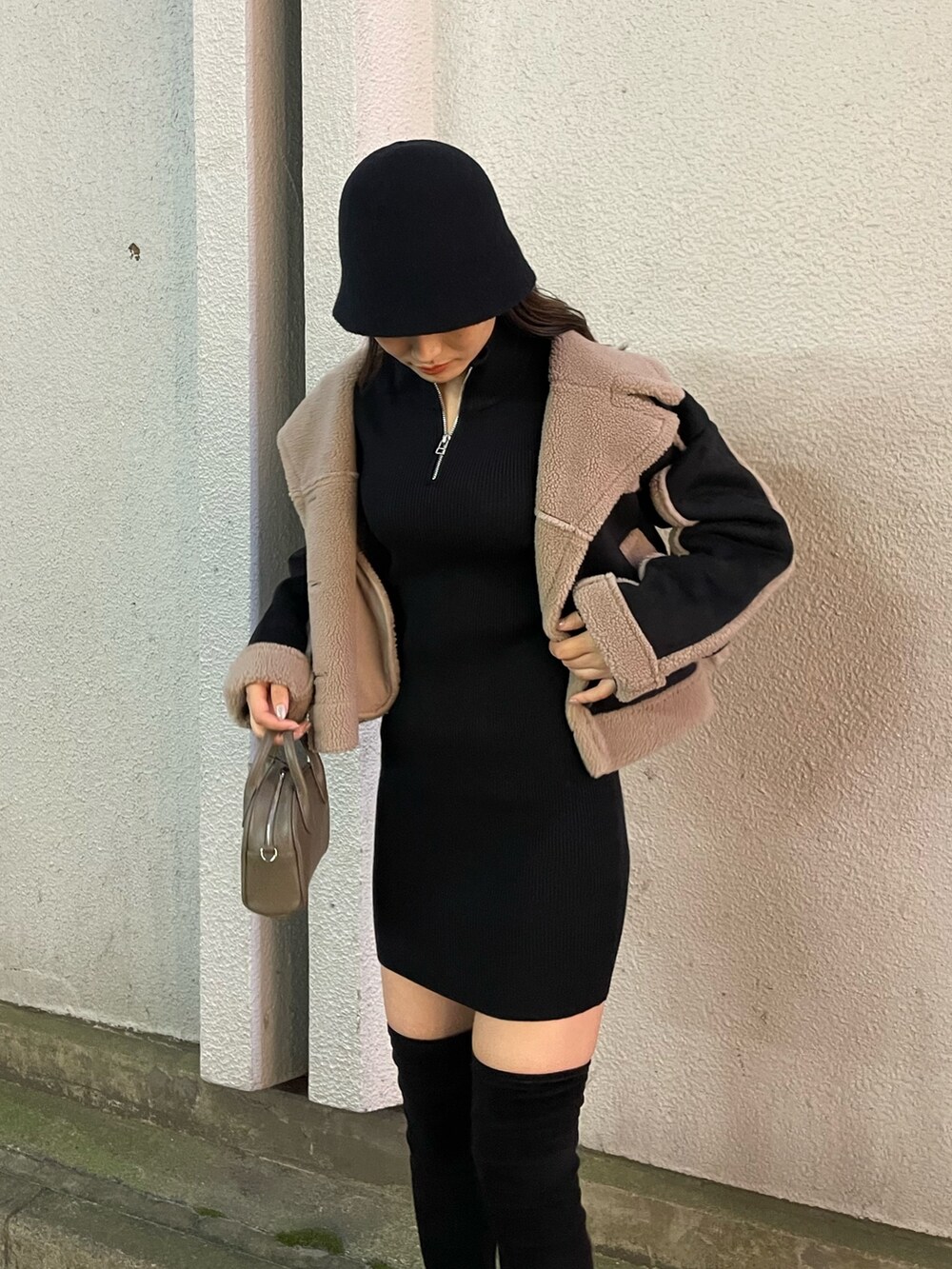 ブラック系のムートンコート、ブラウン系のハンドバッグ、ブラック系のブーツを着用したレディースの秋コーディネートの4枚目の写真