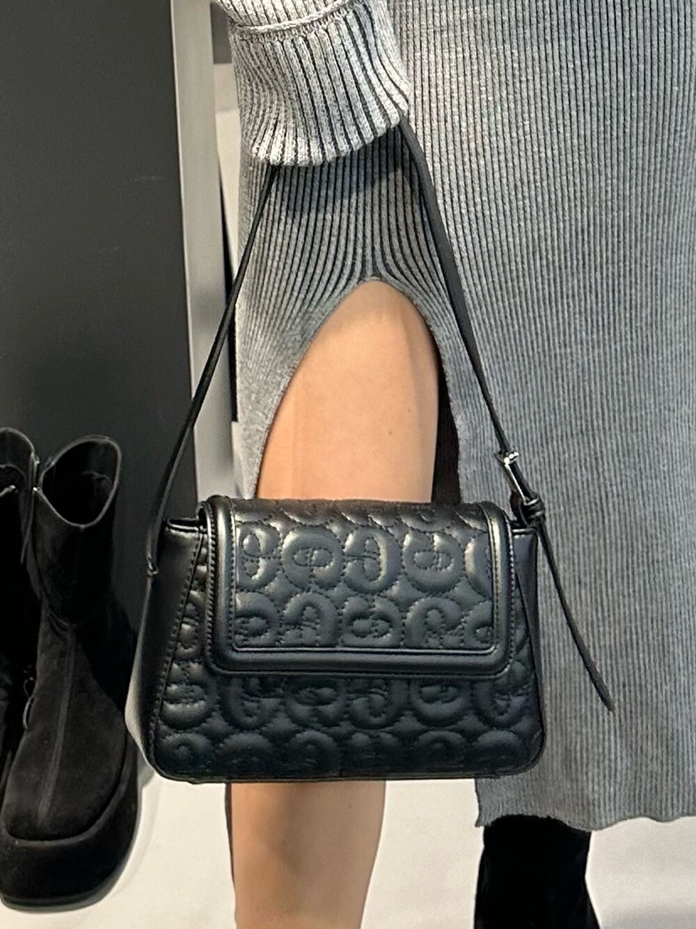 グレー系のワンピース、ブラック系のブーツ、ブラック系のハンドバッグを着用したレディースの冬コーディネートの6枚目の写真