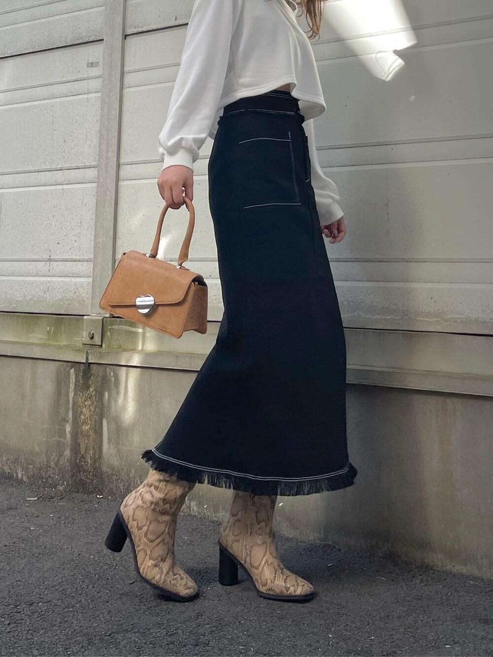 ブラック系のスカート、ホワイト系のTシャツ/カットソー、ブラウン系のハンドバッグを着用したレディースの冬コーディネートの5枚目の写真