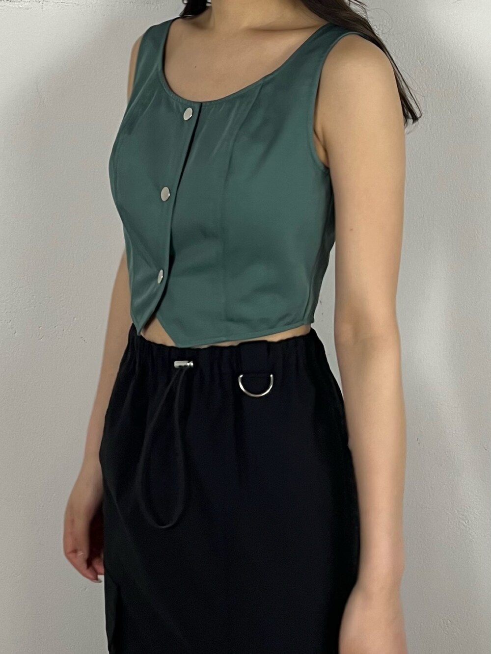 ブラック系のスカート、グリーン系のキャミソール、ブラック系のブーツを着用したレディースの春コーディネートの5枚目の写真