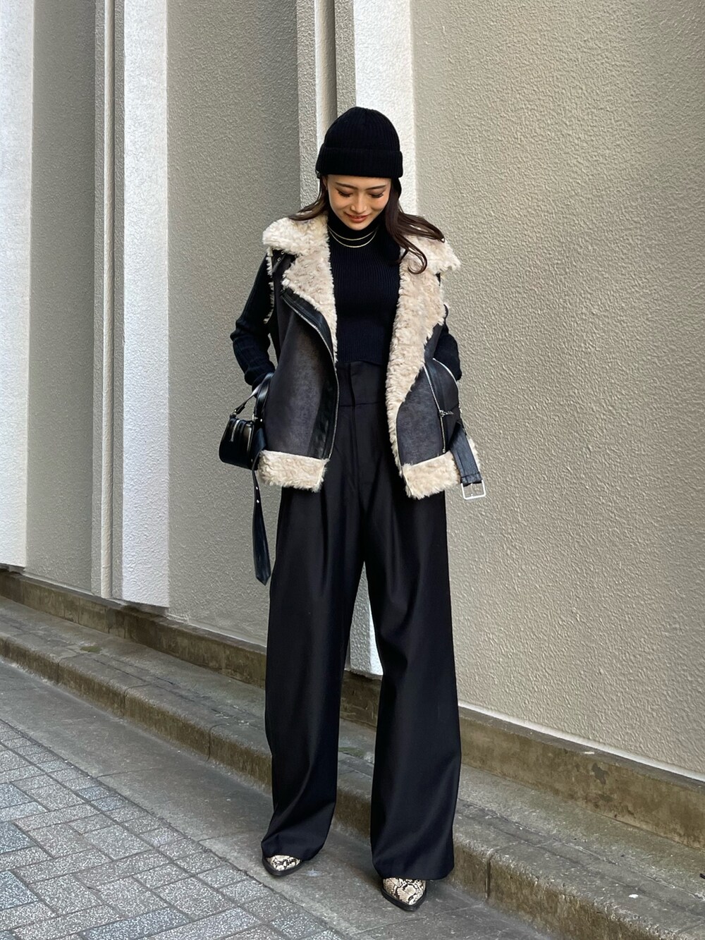 ブラック系のニット/セーター、ブラック系のその他パンツ、ブラック系のハンドバッグを着用したレディースの冬コーディネートの2枚目の写真