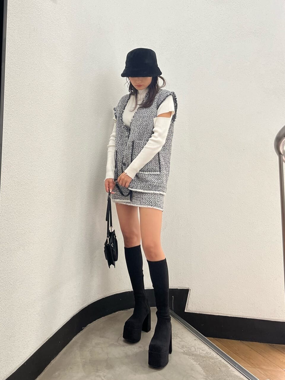ホワイト系のニット/セーター、ブラック系のブーツ、グレー系のベストを着用したレディースの秋コーディネートの2枚目の写真