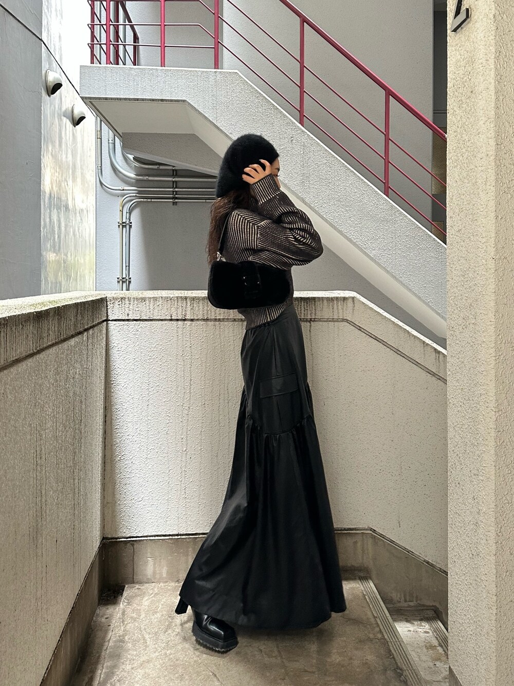 ブラック系のスカート、ブラック系のニット/セーター、ブラック系のハンドバッグを着用したレディースの秋コーディネートの3枚目の写真